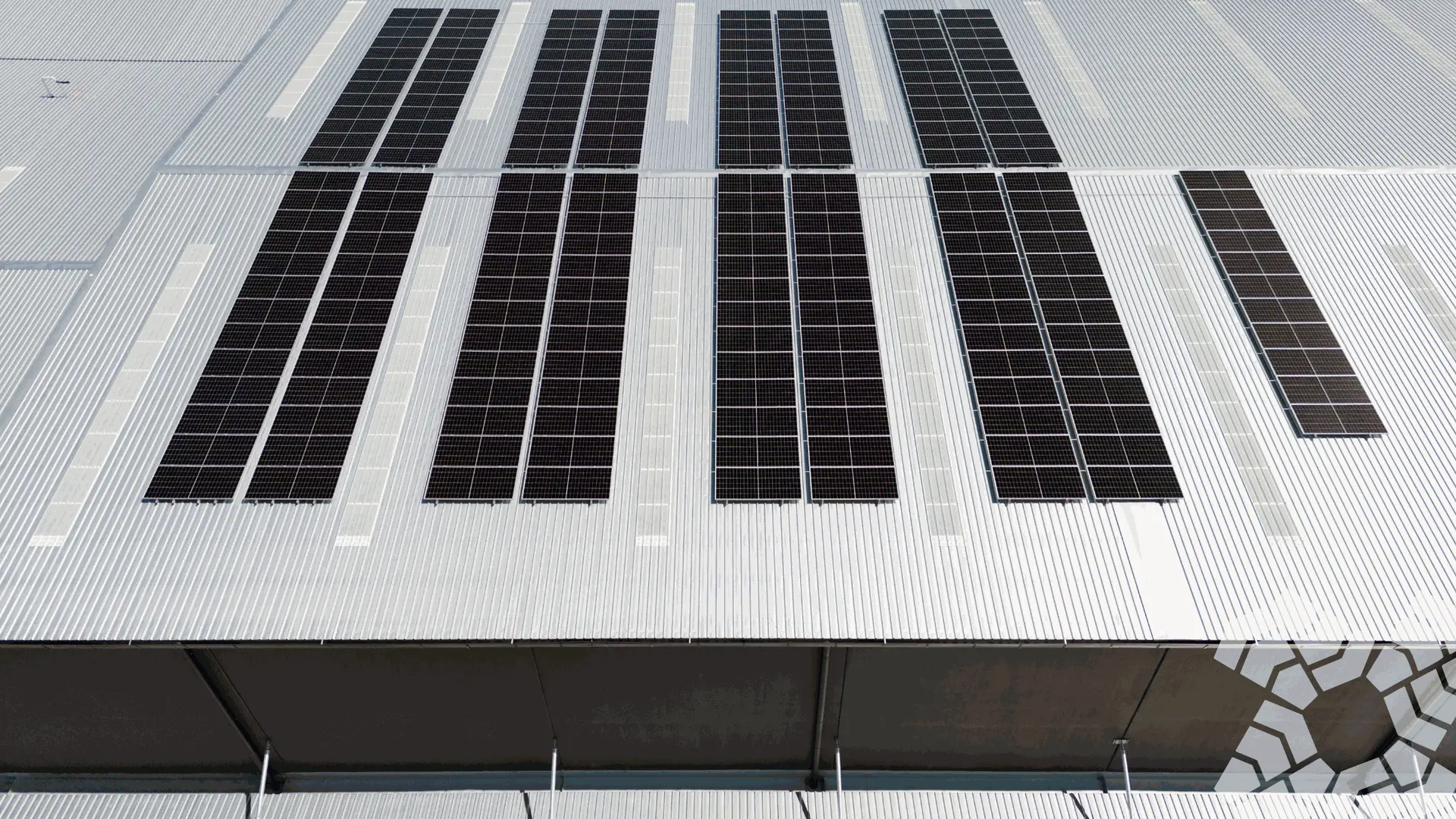 Instalación solar sobre nave industrial en operación continua – industria manufacturera. Fábrica industrial con techos equipados con paneles solares operando durante el día. La imagen muestra infraestructura robusta, maquinaria activa y aprovechamiento pleno de energía solar en horario laboral.